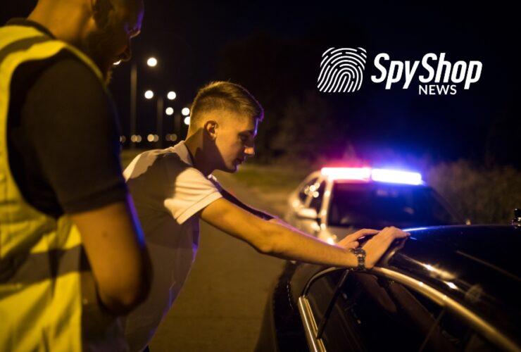 Młody mężczyzna, który został zatrzymany do kontroli policyjnej, opiera się dłońmi o swój samochód. Policjant go spisuje. Jest noc.